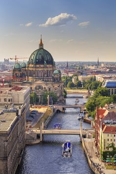 a river running through a city next to tall buildings and a bridge with a dome on top