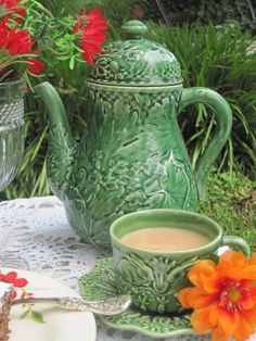 a green tea pot sitting on top of a table next to a cup and saucer