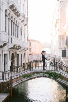 a man standing on a bridge over a small canal in venice, italy with an umbrella