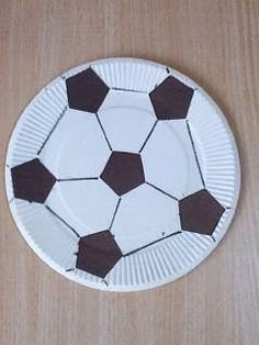 a paper plate with a soccer ball design on the front and sides, sitting on a wooden surface