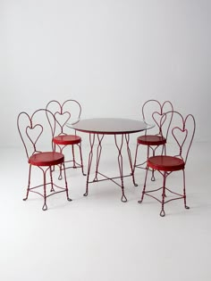 a table and four chairs with hearts on the backrests, against a white background