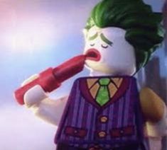 the lego batman movie character has green hair and is holding a toothbrush in his mouth