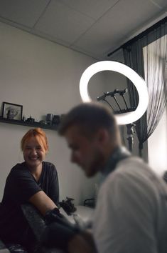 a woman sitting next to a man in a room with a circular light above her