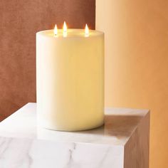 a white candle sitting on top of a marble block