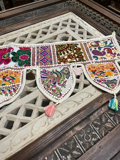 an intricately decorated window frame with tassels and flowers on the outside side