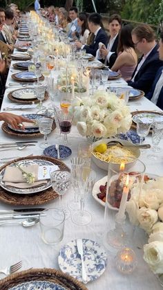 a long table is set with many plates and place settings for an elegant dinner party