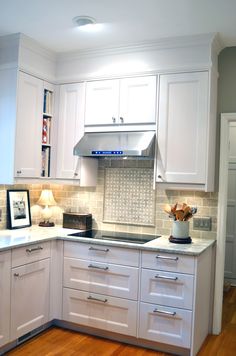 a kitchen with white cabinets and wood floors