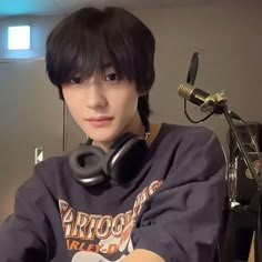 a young man wearing headphones sitting in front of a microphone