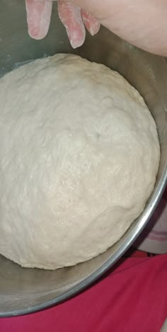 someone is kneading dough into a metal bowl on top of a pink blanket