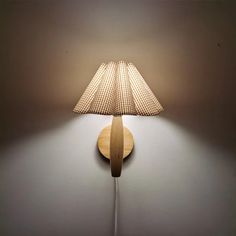 a lamp that is sitting on the wall next to a light fixture with a wooden base