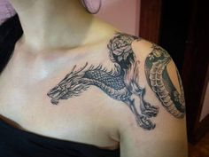 a woman with a dragon tattoo on her shoulder and chest is looking at the camera