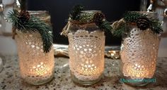 three mason jars with pine cones and lights in them sitting on a table next to a mirror