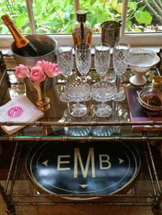 a bar cart filled with wine glasses and personalized items for guests to use on their wedding day