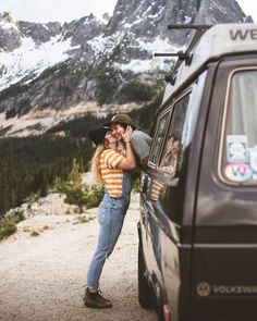 a man and woman kissing in the back of a pick up truck on a dirt road