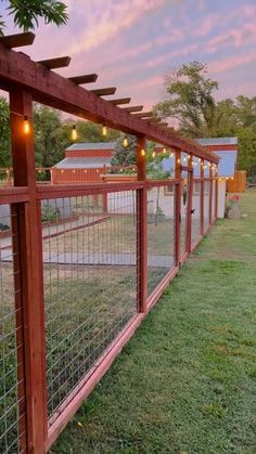 a wooden fence with lights hanging from it's sides on the grass in front of a house