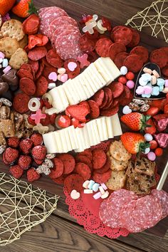 a heart shaped platter filled with lots of different types of cheeses and crackers