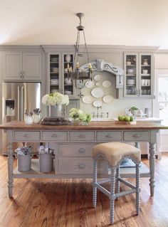 a kitchen island with two stools in front of it and plates on the wall