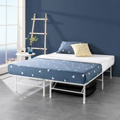 a bed that is in a room with blue walls and white furniture on the floor