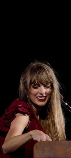 a woman with long blonde hair and red dress smiling in front of a piano keyboard