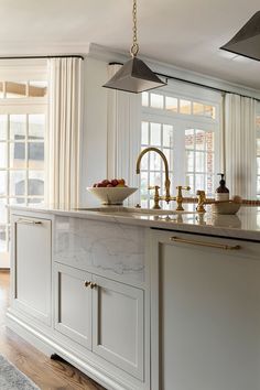 a kitchen with marble counter tops and gold faucet lighting over the sink area