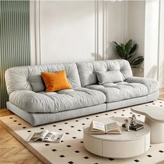 a white couch sitting on top of a rug in a living room next to a table