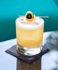 a cocktail with an olive garnish on the top