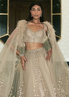 Our Eden lehenga fully embellished with delicate embroideries. Paired up with asymmetric embellished cape. Embellished Lehenga With Cape Sleeves For Festivals, Festive Embellished Lehenga With Cape Sleeves, Designer Lehenga With Sequins And Cape Sleeves, Festive Lehenga With Sequins And Cape Sleeves, Sequined Sharara With Cape Sleeves For Receptions, Designer Wear Choli With Cape Sleeves For Festivals, Reception Sets With Cape Sleeves For Festivals, Festival Choli With Cape Sleeves For Reception, Reception Gown With Sequins And Cape Sleeves