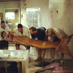 a group of people standing around a big fish