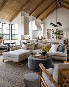 a living room filled with lots of furniture and large windows in the wall above it