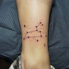 a small tattoo on the foot of a person with stars in the shape of a zodiac sign