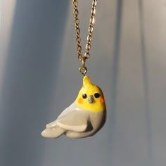 a yellow and gray bird is hanging from a chain on a white surface with shadows