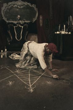 a man in white shirt laying on top of a floor next to a chalk drawing