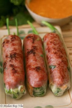 three sausage rolls on a plate with dipping sauce