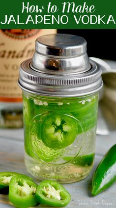 a mason jar filled with green liquid next to cucumbers