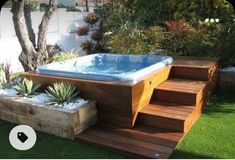 a hot tub sitting on top of a wooden deck next to a lush green yard