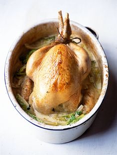 a whole chicken in a pot with broccoli and onions