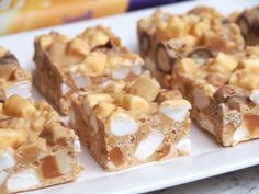 several pieces of dessert sitting on a white plate next to a box of cereal bars