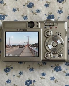 a digital camera sitting on top of a flowered cloth covered tablecloth next to a window