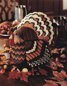 a knitted turkey hat sitting on top of a table next to nuts and leaves