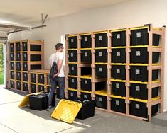 a man standing in front of shelves filled with black and yellow bins next to each other