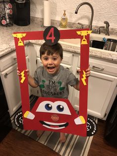 a young boy is holding up a cardboard car