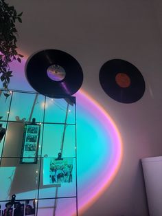 two vinyl records are hanging on the wall in front of a mirror with light coming through it