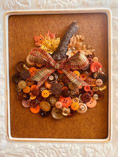 a pile of buttons in a white frame with a bow on the front and bottom