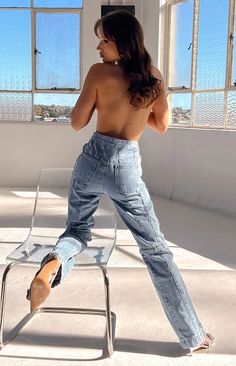 a shirtless woman is sitting on a chair in an empty room and looking out the window