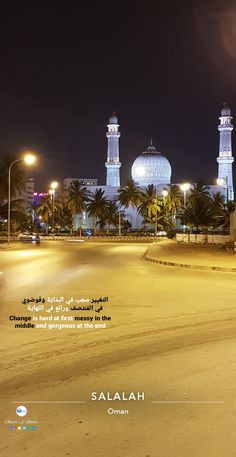 two tall white buildings sitting in the middle of a street at night with palm trees