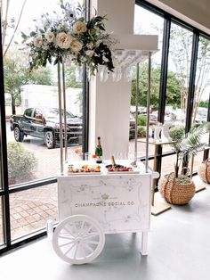 a white cart filled with food and drinks sitting in front of a large window next to a sidewalk