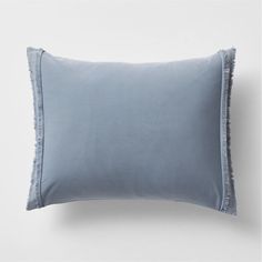 a light blue pillow with fringe trim