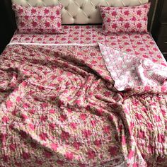 a bed covered in pink and white floral bedspread with matching pillowcases