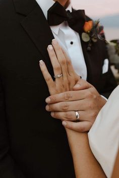 the bride and groom are holding their hands close to each other with rings on their fingers