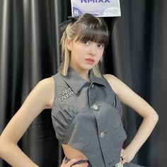 a young woman posing in front of a black backdrop with a sign on her head